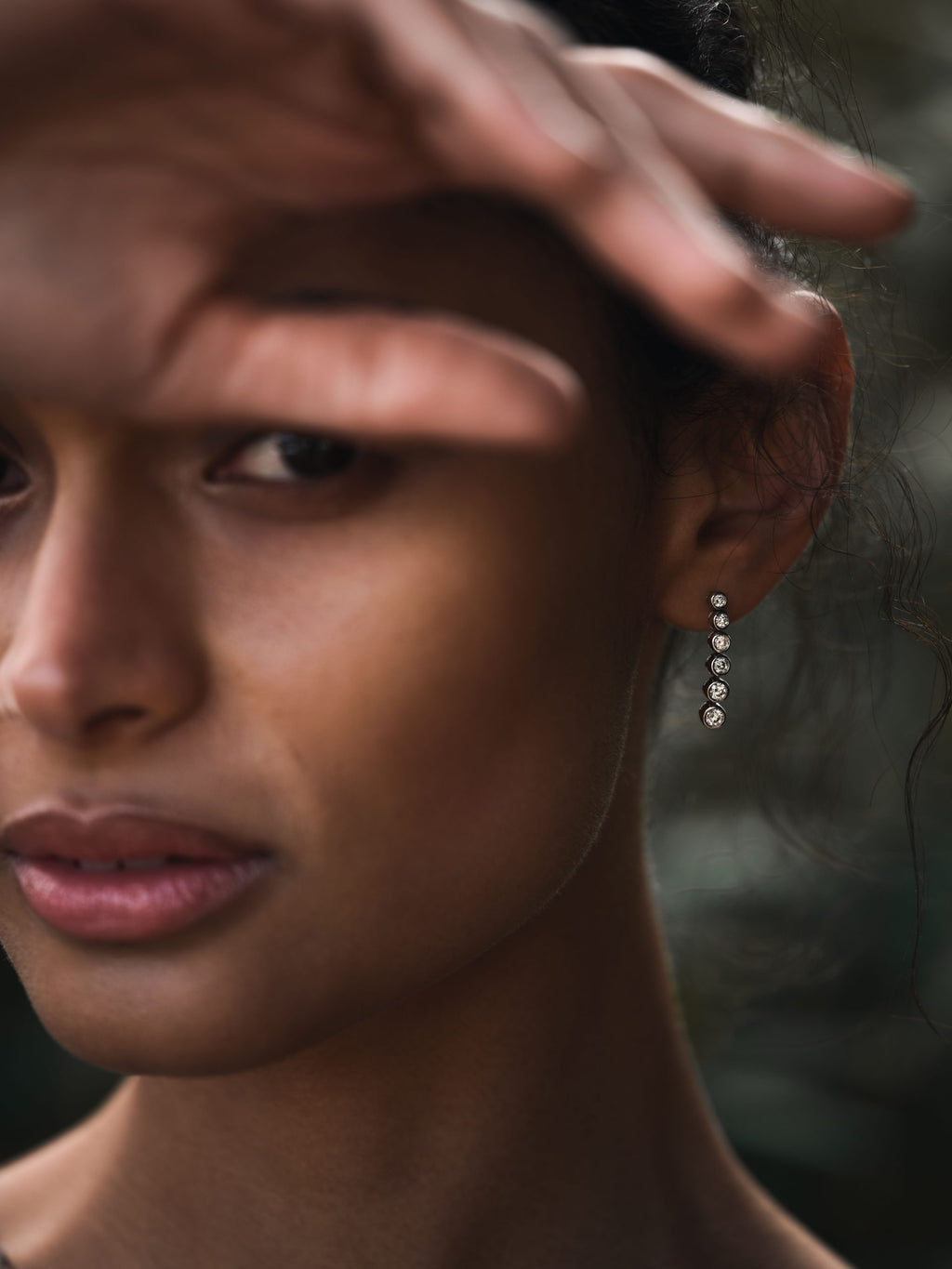 woman wearing rubover setting diamond earrings
