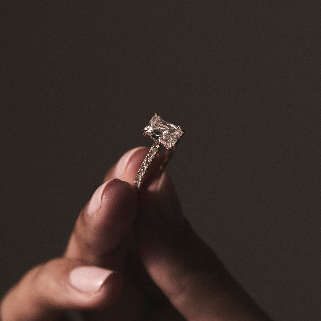 woman holding emerald cut diamond ring