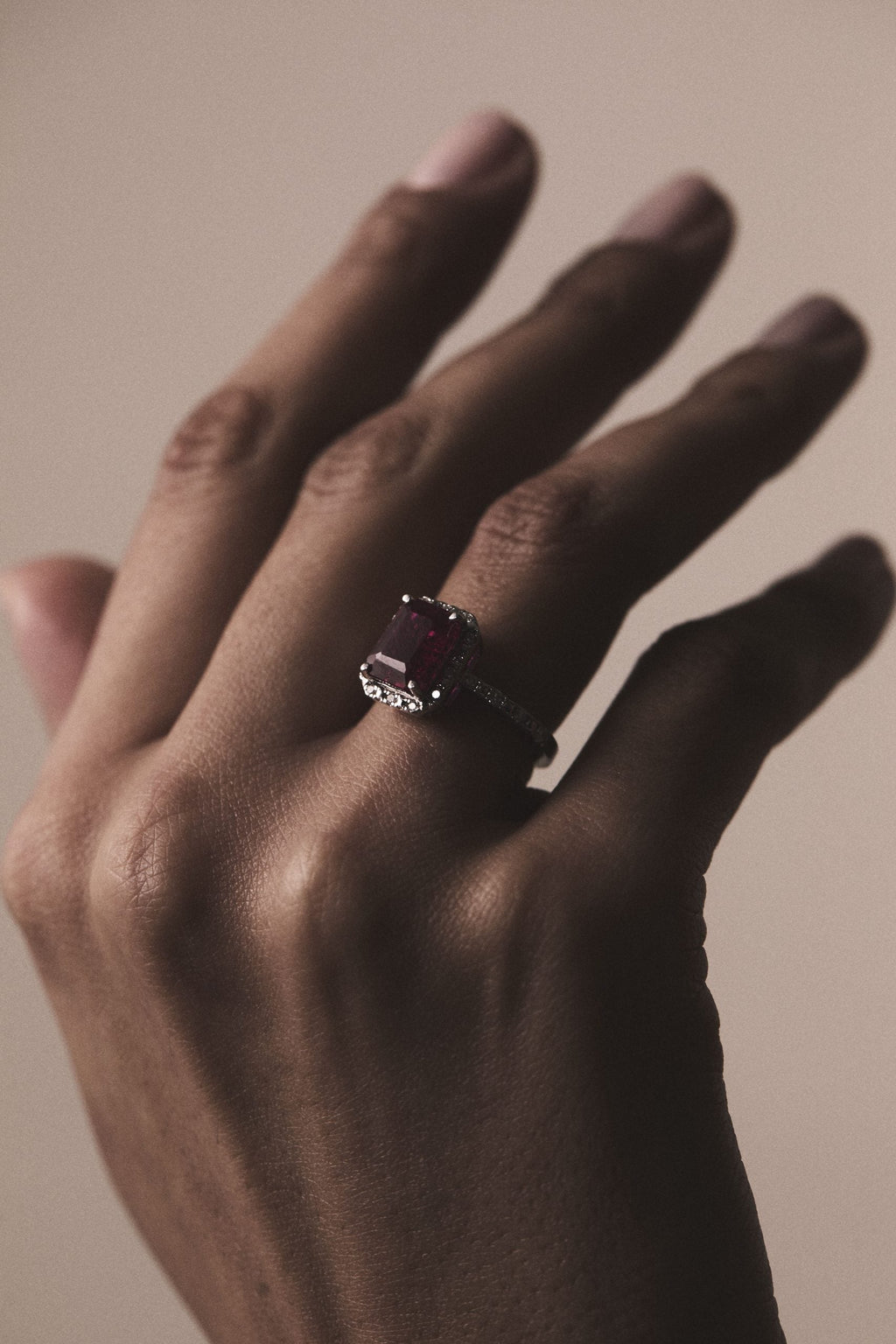 Blue sapphire diamond halo ring shown in a hand