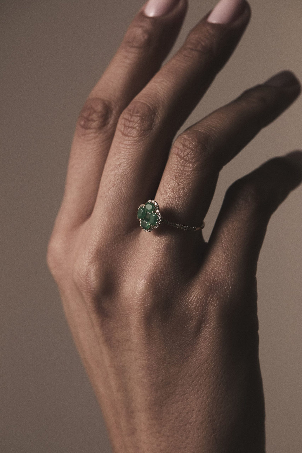 hand with an emerald clover yellow gold ring