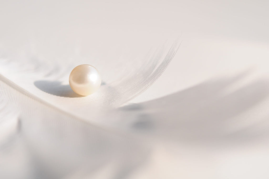 Single Pearl on Feather Background