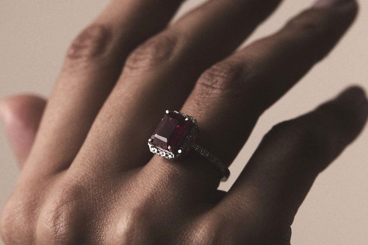 Ruby and diamond halo ring shown in a hand