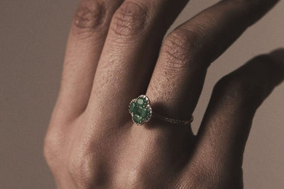 hand with an emerald clover yellow gold ring
