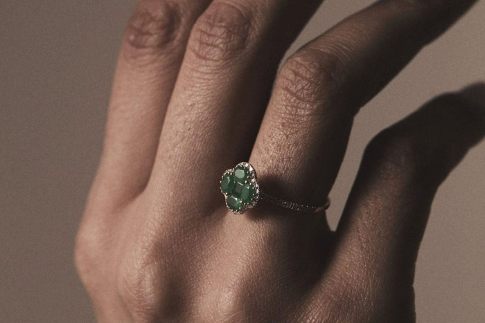 hand with an emerald clover yellow gold ring
